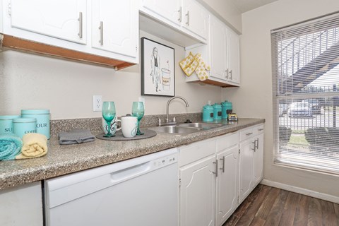 A kitchen with white cabinets and a granite countertop at The Drake in Bossier City, LA